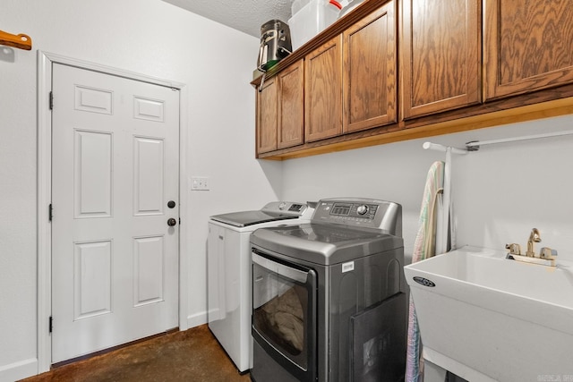 clothes washing area with a textured ceiling, cabinets, sink, and washing machine and clothes dryer