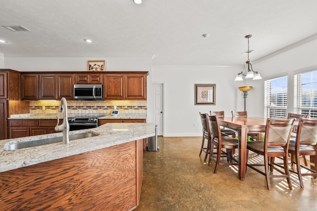 kitchen with sink, hanging light fixtures, light stone countertops, tasteful backsplash, and a notable chandelier