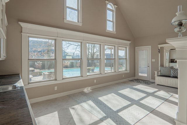 unfurnished living room featuring a wealth of natural light, light tile patterned floors, and a high ceiling