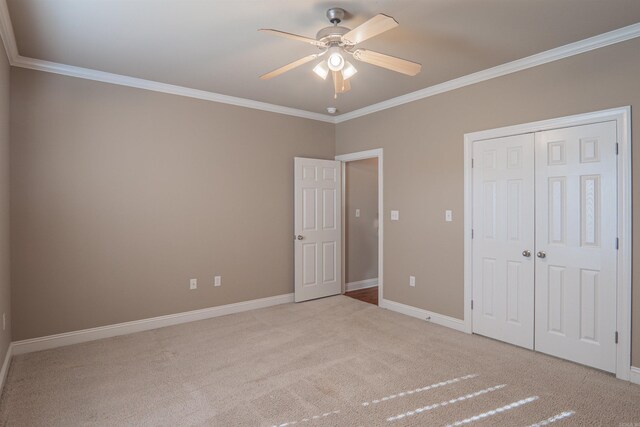 unfurnished bedroom with ornamental molding, a closet, ceiling fan, and light colored carpet