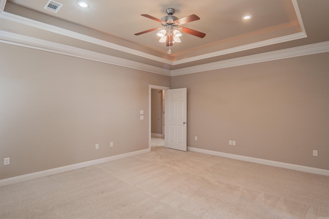 spare room with ceiling fan, a raised ceiling, crown molding, and light carpet