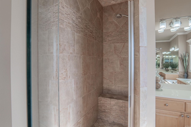 bathroom with tiled shower, vanity, and crown molding