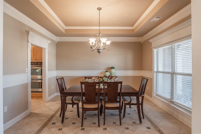 dining area featuring light tile patterned floors, a tray ceiling, an inviting chandelier, and crown molding