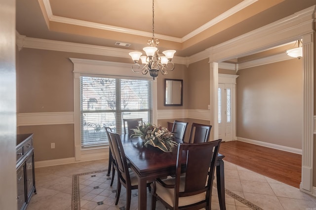 dining room featuring a raised ceiling, light tile patterned flooring, a chandelier, and ornamental molding