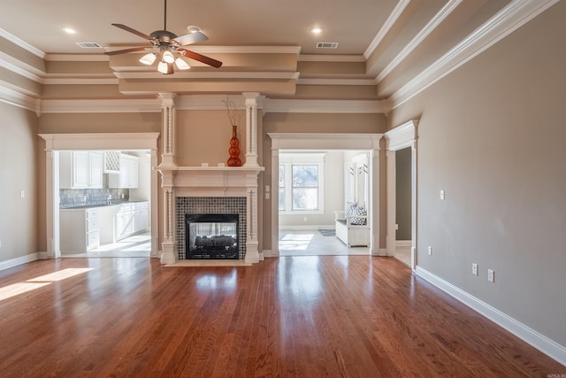 unfurnished living room featuring a tiled fireplace, ceiling fan, hardwood / wood-style floors, and ornamental molding