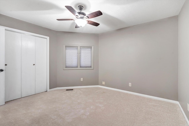 unfurnished bedroom featuring ceiling fan, a closet, and light colored carpet