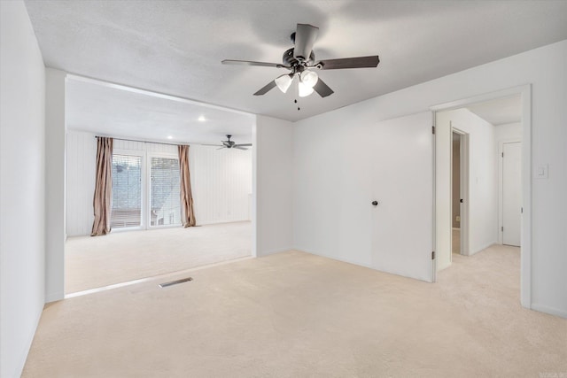 carpeted spare room with a textured ceiling, visible vents, and a ceiling fan