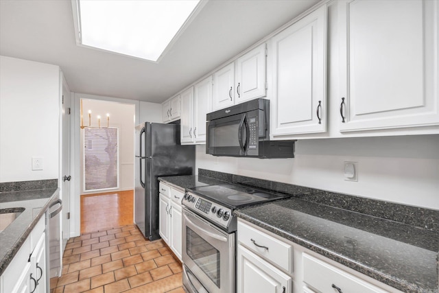 kitchen with dark stone countertops, a chandelier, white cabinets, and black appliances