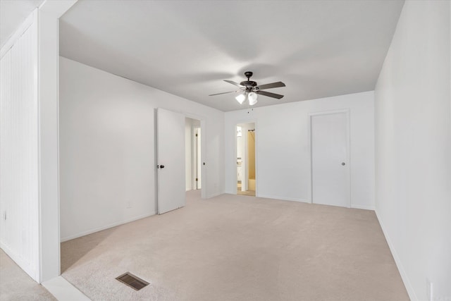 empty room featuring light colored carpet, visible vents, ceiling fan, and baseboards