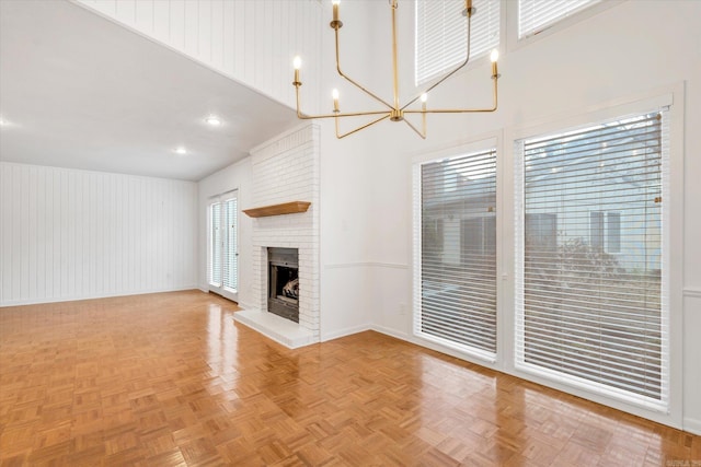 unfurnished living room featuring a chandelier, a fireplace, a towering ceiling, and baseboards