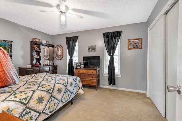 bedroom featuring a closet, a textured ceiling, light colored carpet, and ceiling fan