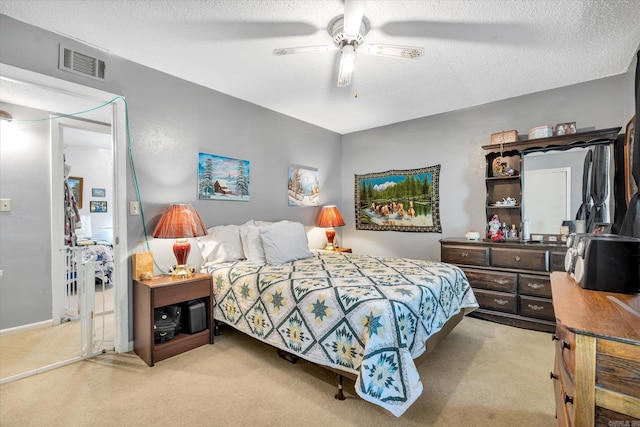 bedroom with ceiling fan, light colored carpet, and a textured ceiling