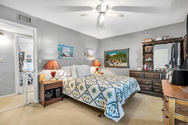 bedroom featuring a textured ceiling, light colored carpet, and ceiling fan