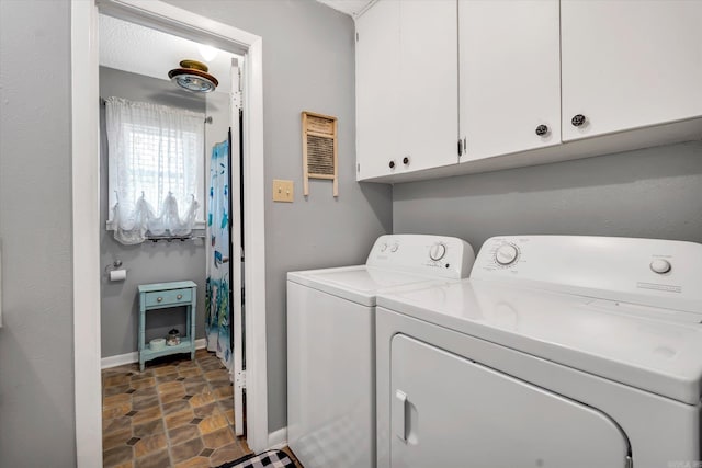 clothes washing area with cabinets and washing machine and dryer