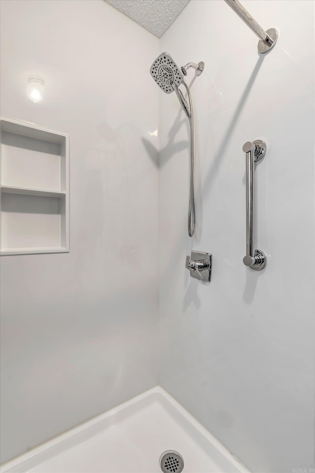 details with a textured ceiling and walk in shower