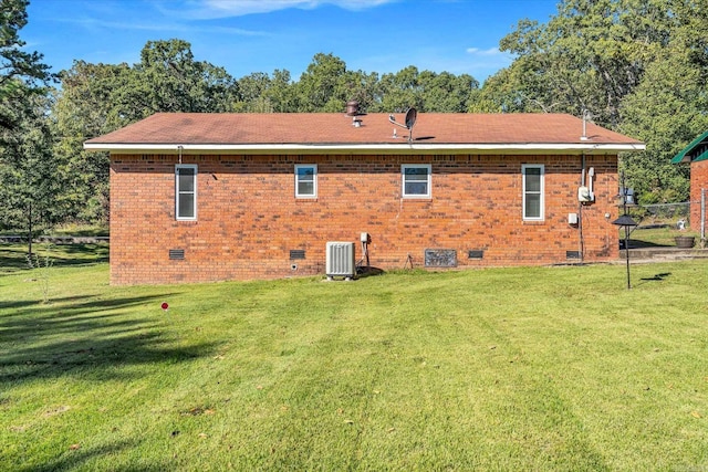 back of property with central AC unit and a lawn