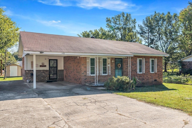 ranch-style home featuring a carport, a storage unit, and a front lawn