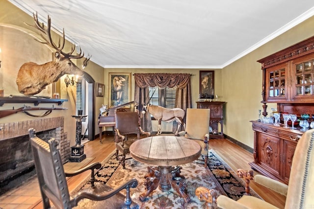 living room with a brick fireplace, light hardwood / wood-style flooring, and ornamental molding