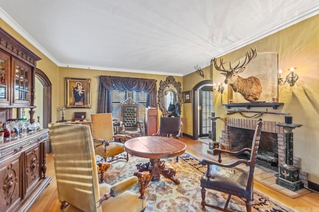 living area featuring a fireplace, light wood-type flooring, and ornamental molding