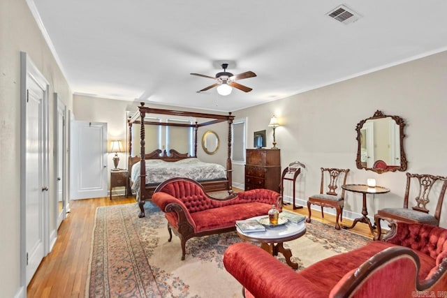 bedroom with light wood-type flooring, ceiling fan, and crown molding