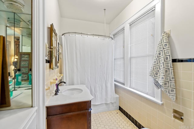 bathroom with tile patterned flooring, vanity, tile walls, and shower / tub combo with curtain