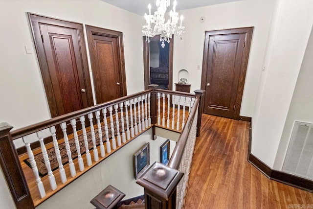 hall with hardwood / wood-style floors and a notable chandelier