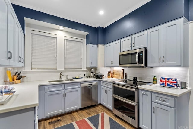 kitchen featuring decorative backsplash, sink, light wood-type flooring, and appliances with stainless steel finishes