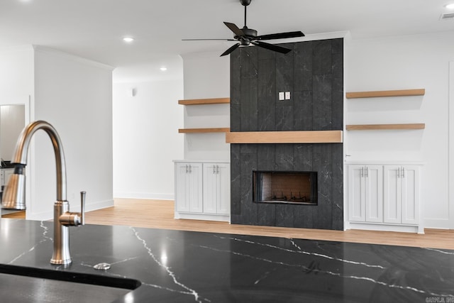 interior space with crown molding, ceiling fan, built in features, light hardwood / wood-style floors, and a tiled fireplace