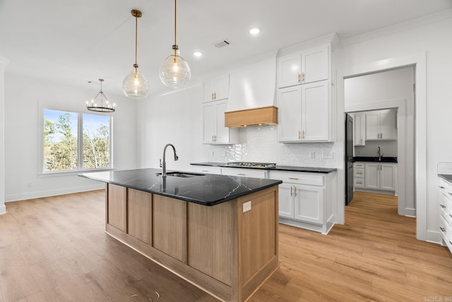 kitchen featuring white cabinetry, sink, and a center island with sink