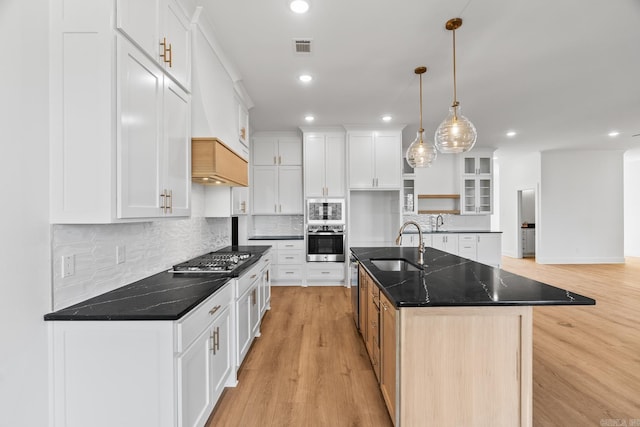 kitchen with appliances with stainless steel finishes, sink, pendant lighting, a center island with sink, and white cabinets