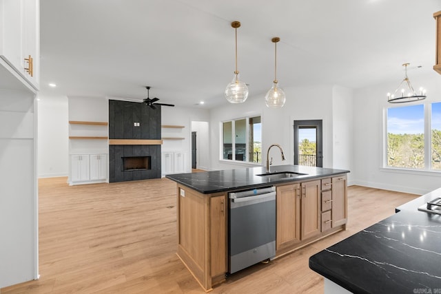 kitchen featuring hanging light fixtures, stainless steel dishwasher, a kitchen island with sink, and sink