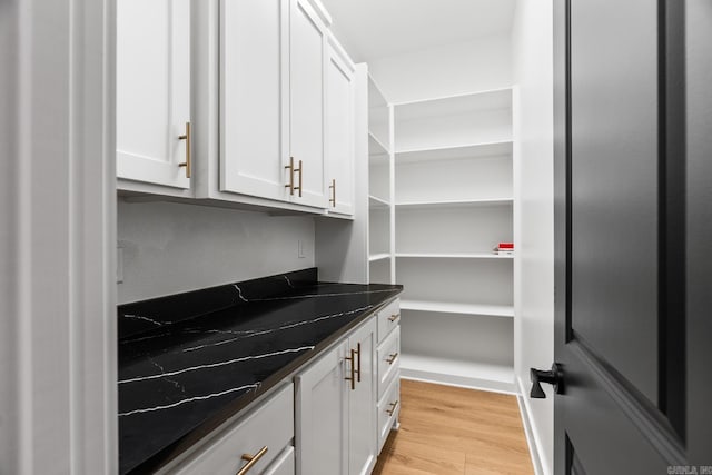 interior space featuring dark stone countertops, white cabinetry, and light wood-type flooring