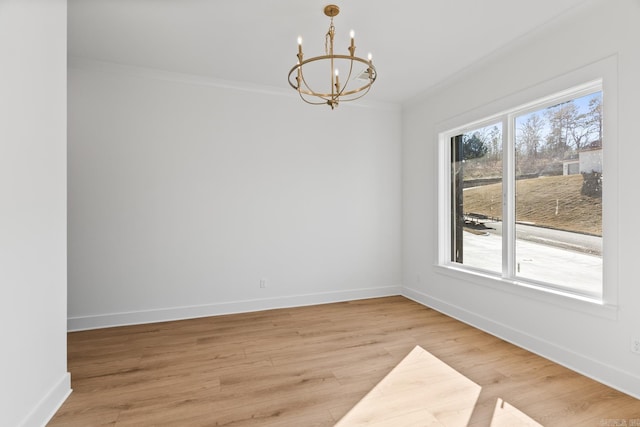 spare room featuring a chandelier, wood-type flooring, and crown molding