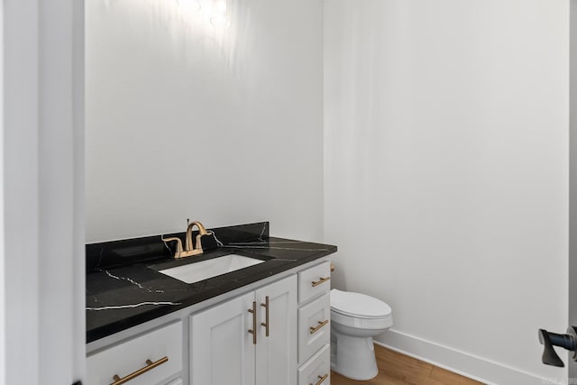 bathroom with hardwood / wood-style floors, vanity, and toilet