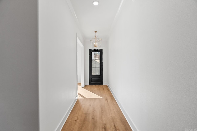 hallway with light hardwood / wood-style floors and an inviting chandelier