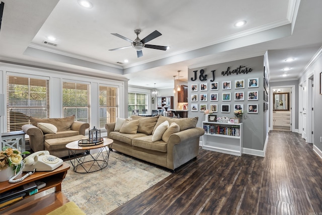 living room featuring crown molding, dark hardwood / wood-style floors, and a tray ceiling