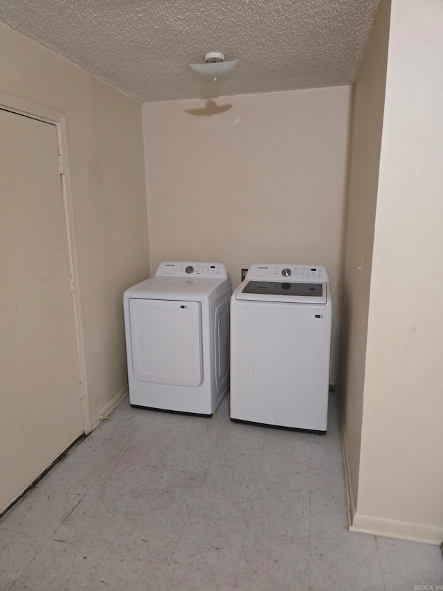 laundry room with washing machine and clothes dryer and a textured ceiling