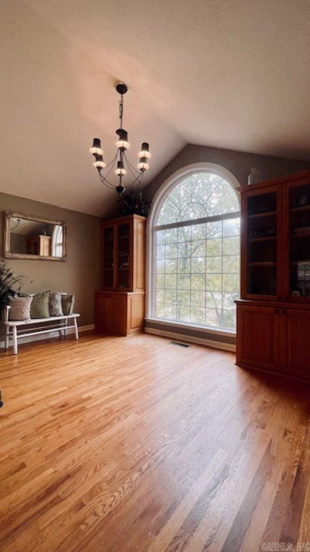 unfurnished dining area with hardwood / wood-style flooring, vaulted ceiling, and an inviting chandelier