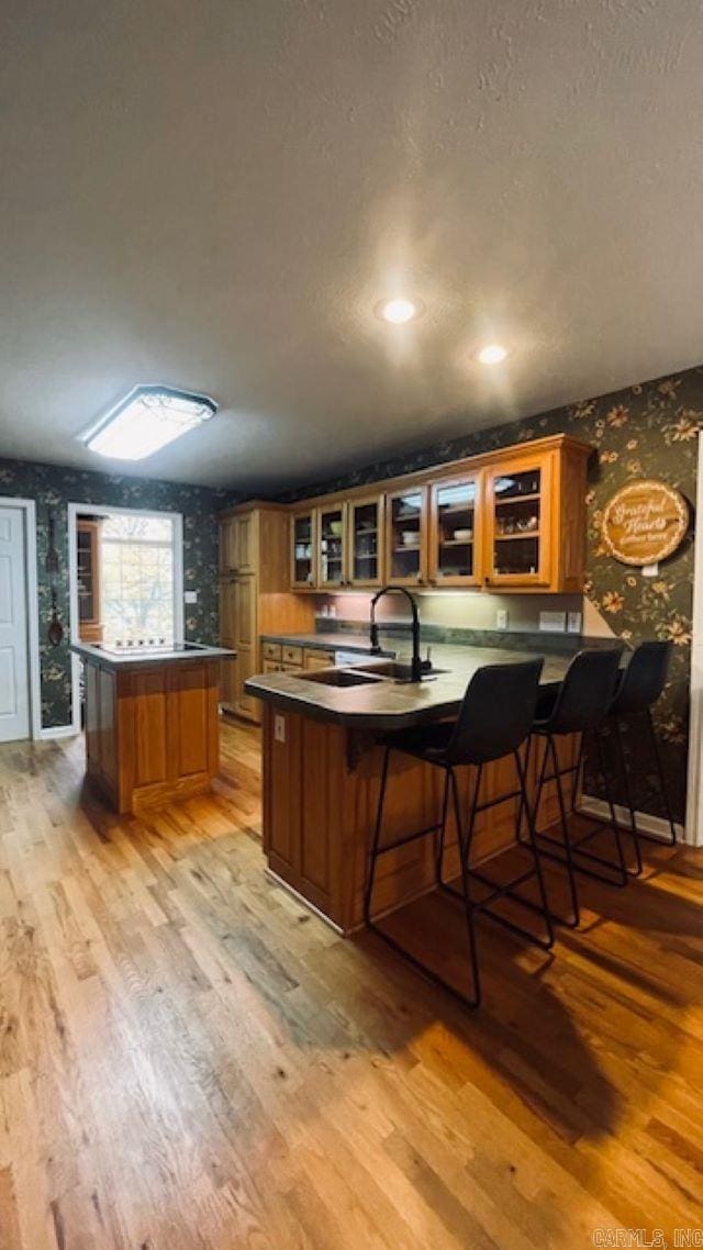 bar featuring light hardwood / wood-style flooring, a textured ceiling, and sink