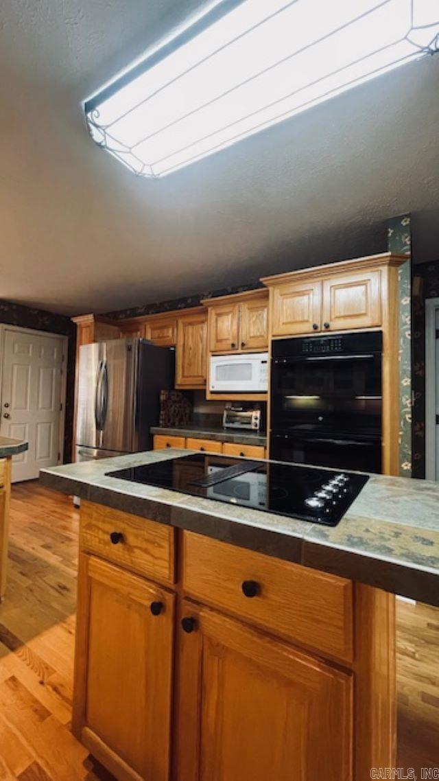 kitchen with black appliances and light hardwood / wood-style flooring