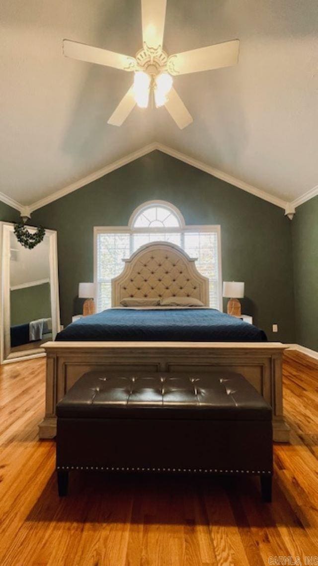 bedroom featuring ceiling fan, light wood-type flooring, ornamental molding, and vaulted ceiling