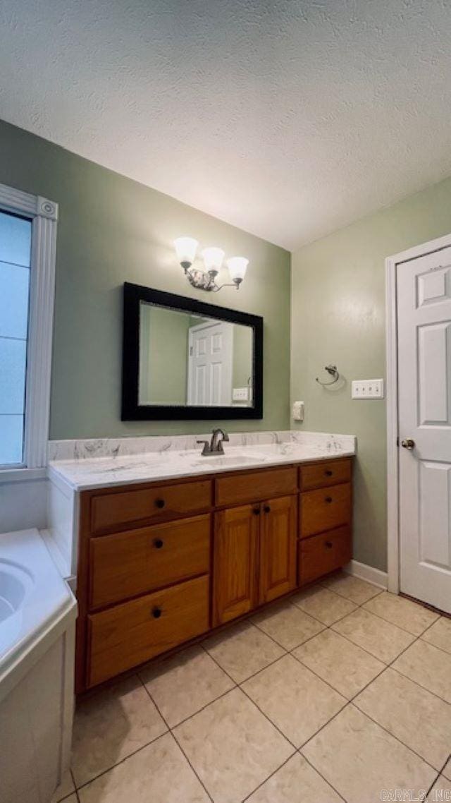 bathroom featuring vanity, tile patterned flooring, a washtub, a textured ceiling, and a chandelier