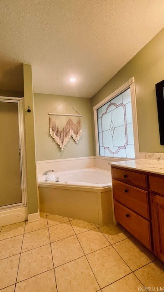 bathroom with plus walk in shower, a textured ceiling, vanity, and tile patterned floors