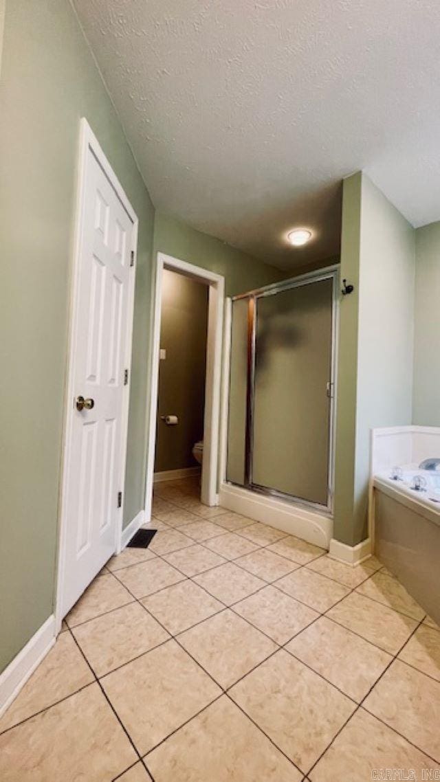 bathroom featuring tile patterned floors, toilet, a textured ceiling, and shower with separate bathtub