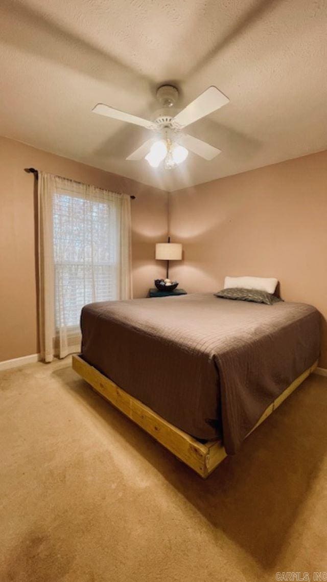 bedroom featuring a textured ceiling, light colored carpet, and ceiling fan