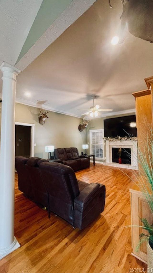 living room with ornate columns, ceiling fan, crown molding, wood-type flooring, and lofted ceiling