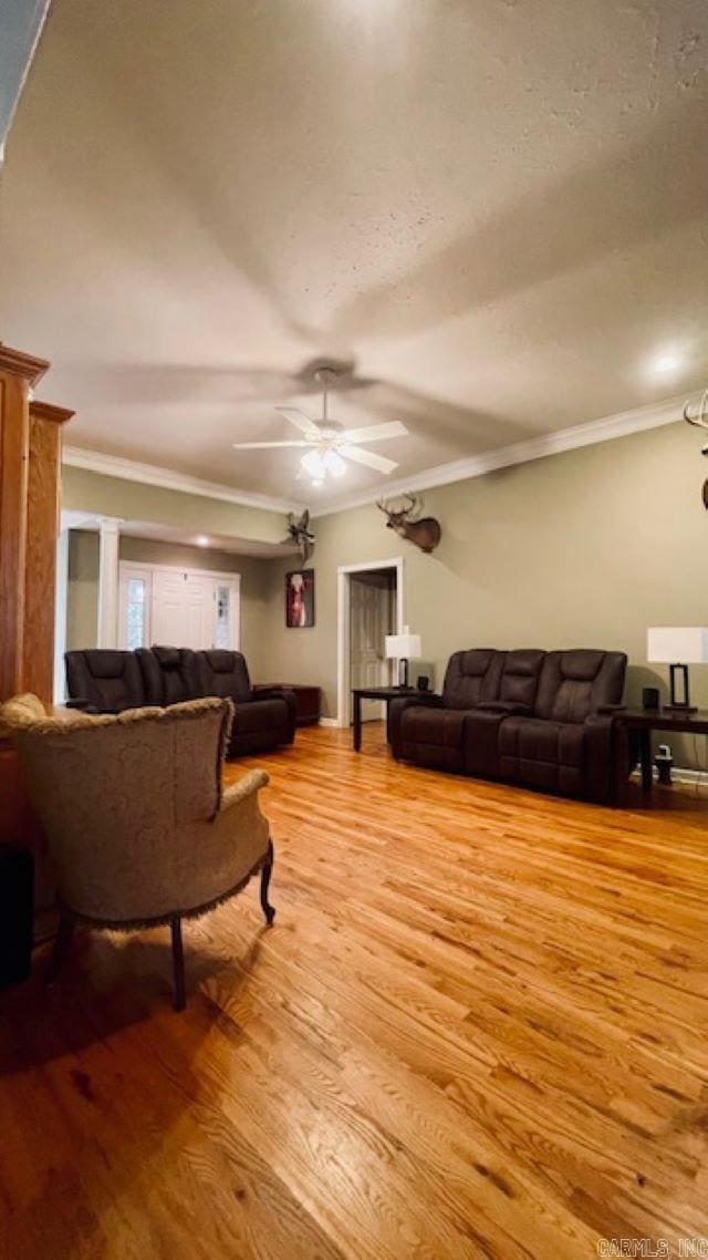 living room with ceiling fan, light hardwood / wood-style flooring, a textured ceiling, and ornamental molding