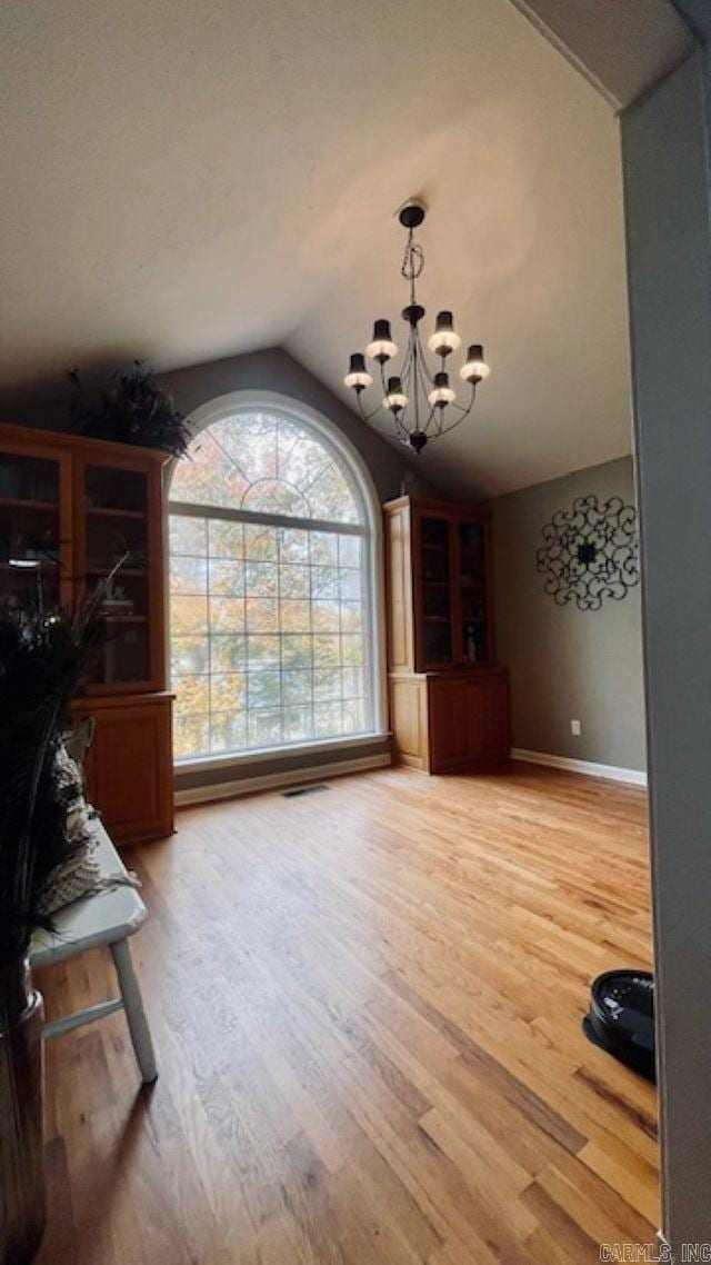 interior space with hardwood / wood-style flooring, lofted ceiling, and a notable chandelier