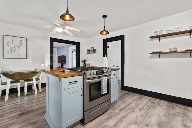 kitchen featuring ceiling fan, butcher block countertops, pendant lighting, stainless steel range with gas stovetop, and light wood-type flooring