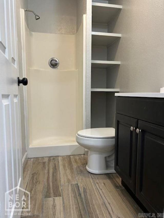 bathroom featuring a shower, hardwood / wood-style floors, vanity, and toilet